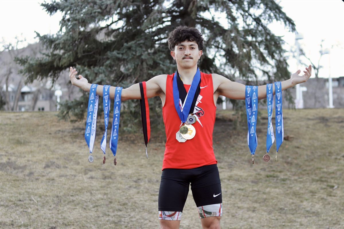 Bryson in a red track uniform with medals around his neck and hanging from both arms